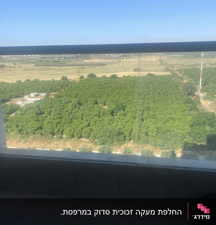 מעקה זכוכית עם נוף לשדה ירוק